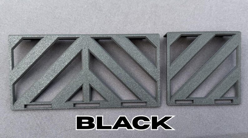 May include: Two black, geometric, metal pieces with a diagonal pattern. The larger piece has a peace sign design in the center. The word "BLACK" is printed in bold, white letters at the bottom.