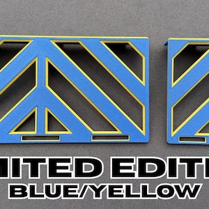 May include: Two blue and yellow geometric shapes with a peace sign design. The text "LIMITED EDITION BLUE/YELLOW" is displayed below the shapes.