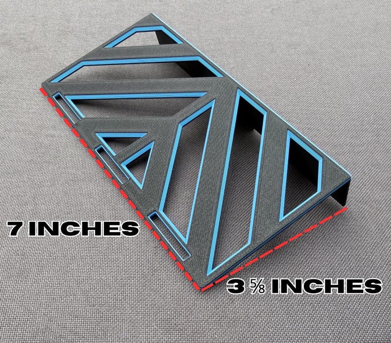 May include: A black and blue geometric design, measuring 7 inches by 3 5/8 inches. The design features a series of angled lines and shapes with blue accents. The edges are outlined in red.