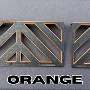 May include: Two decorative wooden panels with a geometric design. The panels are dark gray with orange accents and the word "ORANGE" in white block letters. The panels have a diagonal pattern.