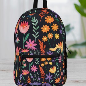 May include: A black backpack with a floral pattern featuring pink, orange, yellow, and purple flowers on a black background.