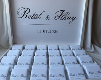 May include: A white rectangular box containing multiple small white square items arranged in rows. The interior lid features the black printed text Betül & İlkay above the date 11.07.2026. Each small item is also printed with the same names and date.