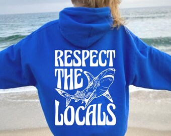 May include: A royal blue hoodie with a white graphic of a shark and the text "Respect the Locals".