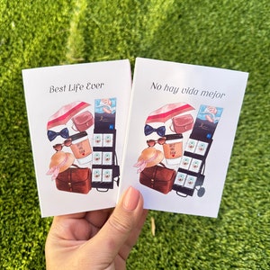 May include: Two cards with illustrations of a woman's summer outfit. The card on the left says "Best Life Ever" and the card on the right says "No hay vida mejor".