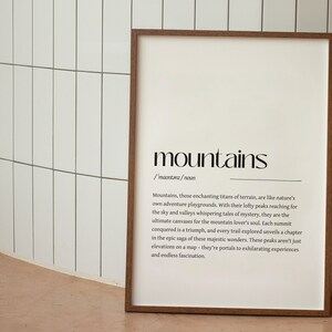 Puede incluir: Una impresi&oacute;n enmarcada con un dise&ntilde;o en blanco y negro. La impresi&oacute;n presenta la palabra "mountains" en una fuente grande, seguida de una definici&oacute;n de la palabra. La definici&oacute;n describe las monta&ntilde;as como "titanes encantadores del terreno" y "portales a experiencias emocionantes".