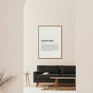 Puede incluir: Una impresi&oacute;n enmarcada con la palabra "monta&ntilde;as" en negrita en negro y una definici&oacute;n de la palabra debajo. La impresi&oacute;n est&aacute; colgada en una pared rosa claro en una habitaci&oacute;n con un sof&aacute; gris y una mesa auxiliar de madera.