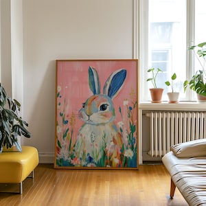 May include: A framed painting of a colorful rabbit with blue ears, surrounded by flowers on a pink background.