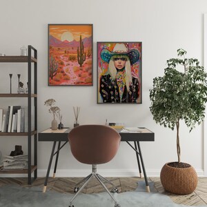 May include: A framed print of a woman wearing a colorful cowboy hat and a black jacket with a desert landscape in the background. The print is hanging on a white wall above a desk with a brown chair.