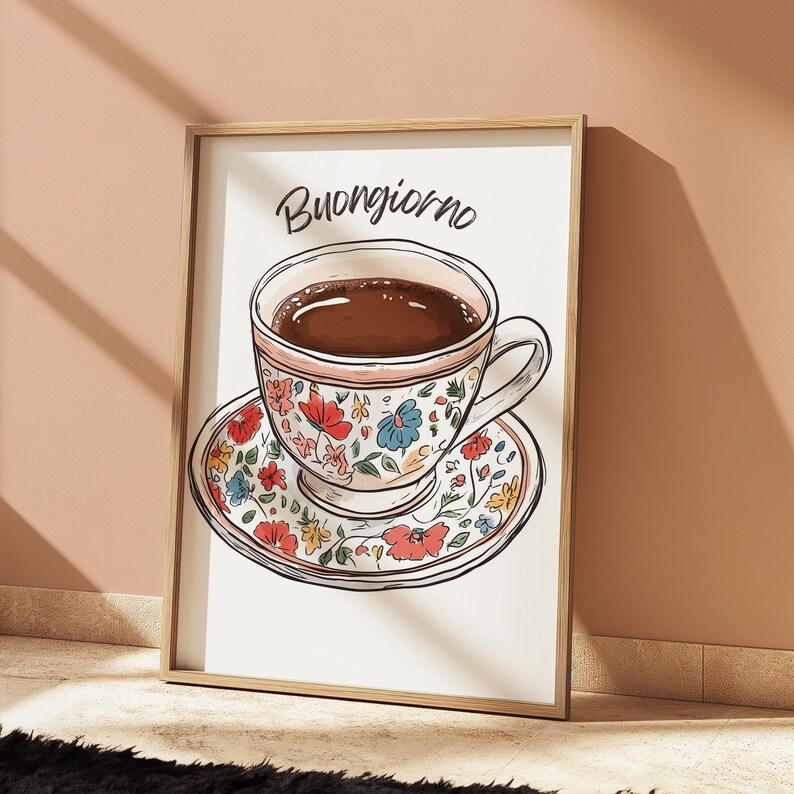 K&ouml;nnte beinhalten: Eine wei&szlig;e Kaffeetasse mit floralem Muster und braunem Kaffee darin, die auf einer passenden Untertasse steht. Der Text "Buongiorno" ist in Schwarz &uuml;ber der Tasse geschrieben.