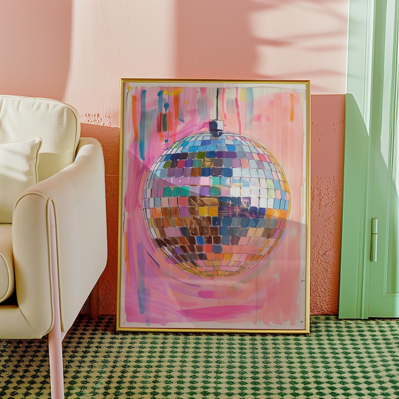 May include: A framed artwork depicting a disco ball with a mosaic design in various colours. The artwork has a gold frame and is set against a pink and white abstract background. The image is in a room with a green patterned carpet and a cream-coloured chair.