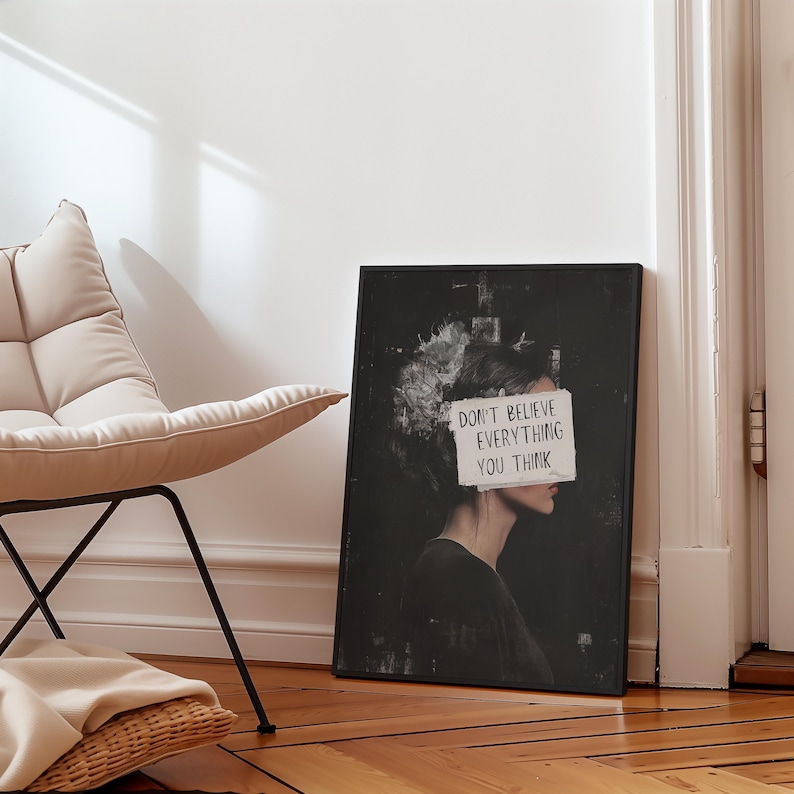 May include: Black and white art print featuring a woman's face with a piece of paper covering her eyes. The paper has the text "Don't believe everything you think" written on it.