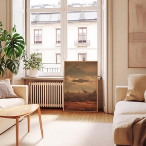 May include: A framed art print depicts a surreal landscape with a dinosaur and a UFO under a cloudy sky. The artwork has a vintage aesthetic, with warm, earthy tones. The print is displayed in a bright, modern living room setting.