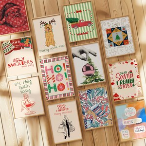 May include: A collection of framed Christmas-themed art prints. The prints feature festive illustrations, including Santa Claus, a dog with antlers, a red truck with a Christmas tree, and the text "Ugly Sweaters xmas party."