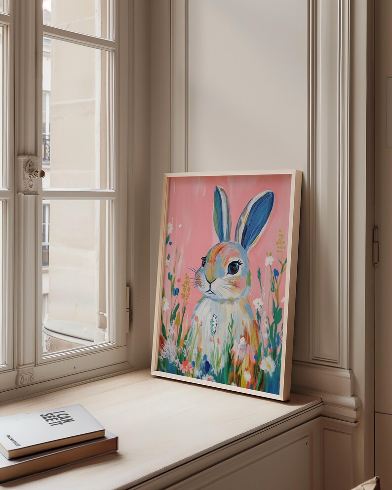May include: A framed painting of a colorful rabbit with blue ears, surrounded by flowers on a pink background.