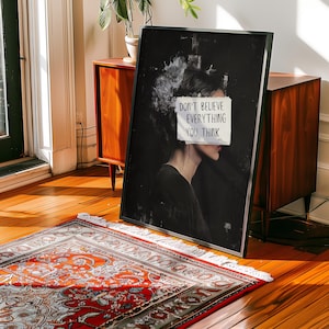 May include: Black and white art print featuring a woman's face with a piece of paper covering her eyes. The paper has the text "Don't believe everything you think" written on it.