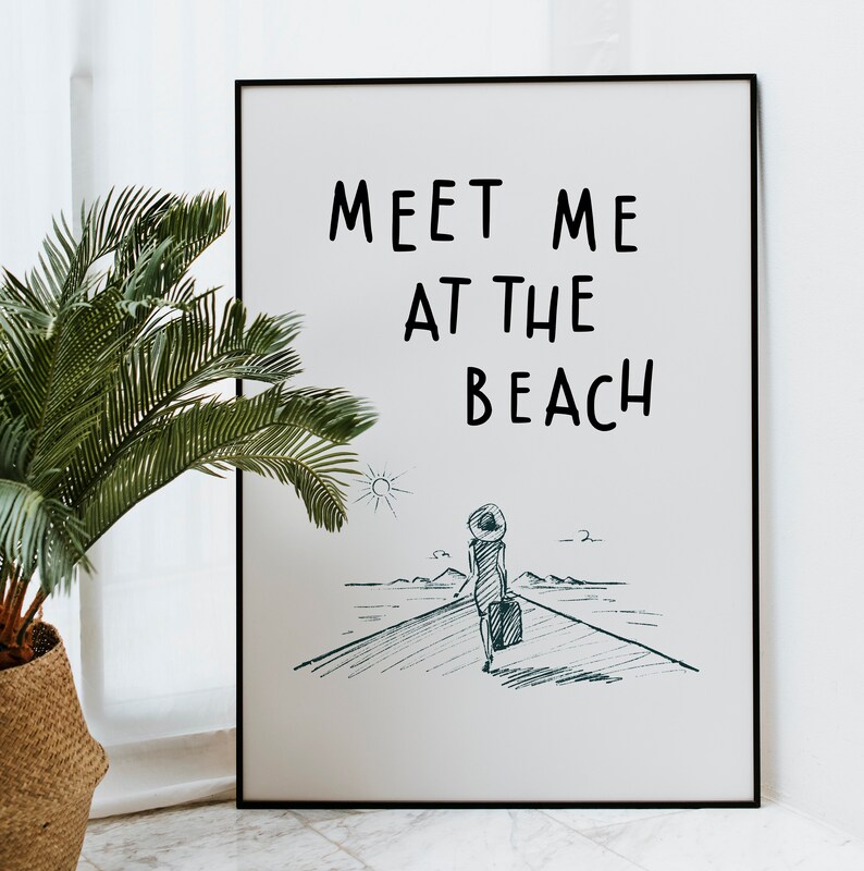 May include: A black framed poster with the text "Meet me at the beach" in white. A hand-drawn illustration of a person walking towards the beach with a suitcase is below the text.