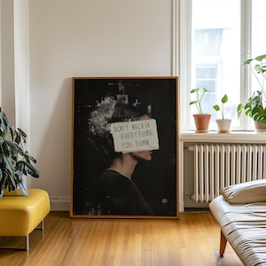 May include: A black and white art print featuring a woman's profile with a piece of paper covering her eyes. The paper has the text "Don't believe everything you think" written on it.