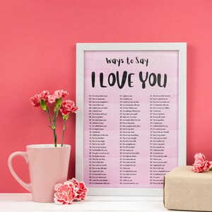 May include: A white framed print with a pink watercolor background and the text "Ways to Say I Love You" with a list of 90 ways to say I love you in black text.