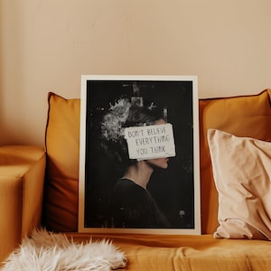 May include: A black and white print of a woman's face with a piece of paper covering her eyes. The paper has the text "Don't believe everything you think" written on it.