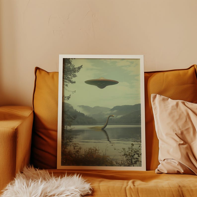 K&ouml;nnte beinhalten: Ein gerahmter Druck, der das Ungeheuer von Loch Ness zeigt, das in einem See schwimmt, mit einer fliegenden Untertasse dar&uuml;ber. Der Druck zeigt einen Wald und Berge im Hintergrund.