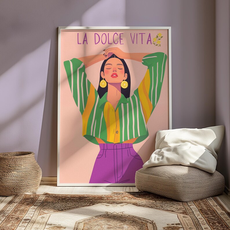 May include: A framed art print featuring a stylized illustration of a person with arms raised. The person wears a green and yellow striped shirt, purple pants, and lemon earrings. The words "LA DOLCE VITA" are at the top.