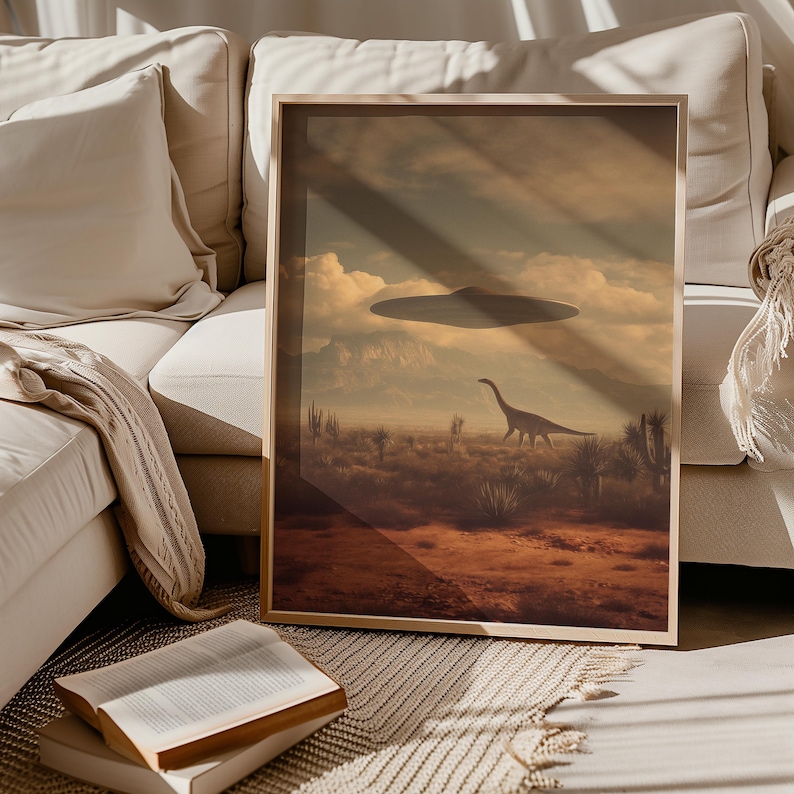 May include: A framed art print depicts a surreal landscape with a dinosaur and a UFO in the sky. The artwork features a desert scene with mountains in the background, rendered in warm, earthy tones. The print is displayed in a wooden frame.