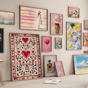 May include: A gallery wall arrangement featuring various framed art prints including a large central poster with red hearts and floral motifs, a print of lemons and coffee, a woman in a white dress, a perfume bottle, and a bouquet in a blue bucket.