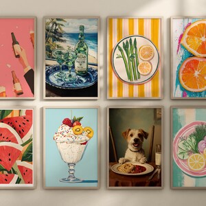 May include: A set of nine framed prints featuring various images, including a bottle of wine, a plate of asparagus, a bowl of fruit, a plate of watermelon, a bowl of ice cream, a dog, and a plate of vegetables. The frames are all white and have a simple design.