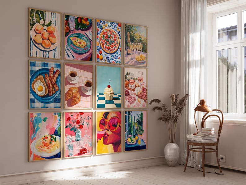 May include: A wall gallery featuring 12 framed prints of colorful, whimsical paintings depicting various food and drink items, including fruit, pizza, pastries, cocktails, and a cupcake. The prints are arranged in a grid pattern on a white wall.