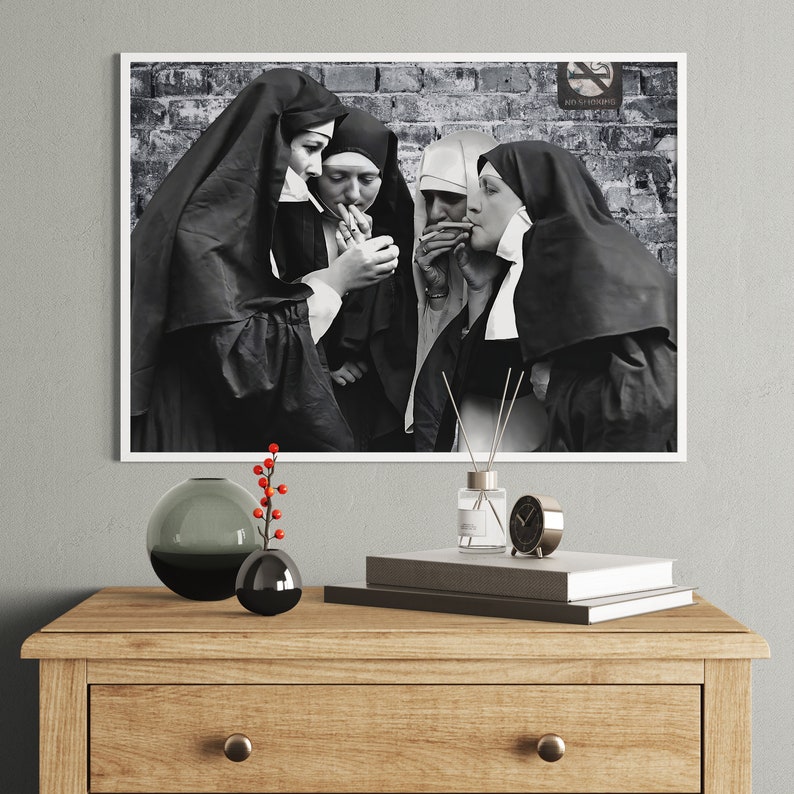 May include: Black and white photograph of four nuns standing together, each holding a cigarette. The nuns are wearing traditional habits and are standing in front of a brick wall.
