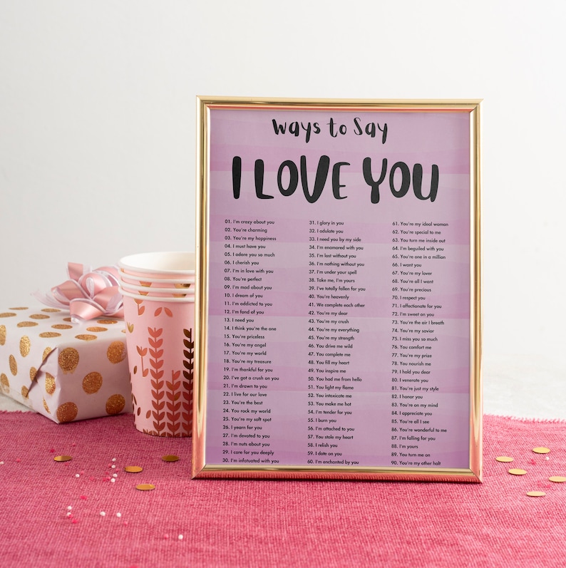 May include: A framed printable with a pink and white ombre background and the text "Ways to Say I Love You" in black. The printable lists 90 different ways to say "I love you" in black text.