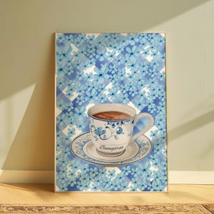 K&ouml;nnte beinhalten: Eine blaue und wei&szlig;e Porzellan-Teetasse mit Untertasse und dem Wort "Buongiorno" auf der Untertasse. Die Tasse ist mit brauner Fl&uuml;ssigkeit gef&uuml;llt und vor einem Hintergrund aus blauen und wei&szlig;en Blumen platziert.