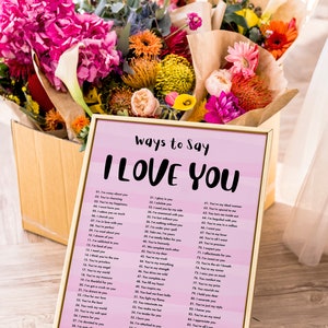 May include: A pink and white printable poster with a gold frame. The poster has the text "Ways to Say I Love You" at the top and a list of 90 different ways to say "I Love You".