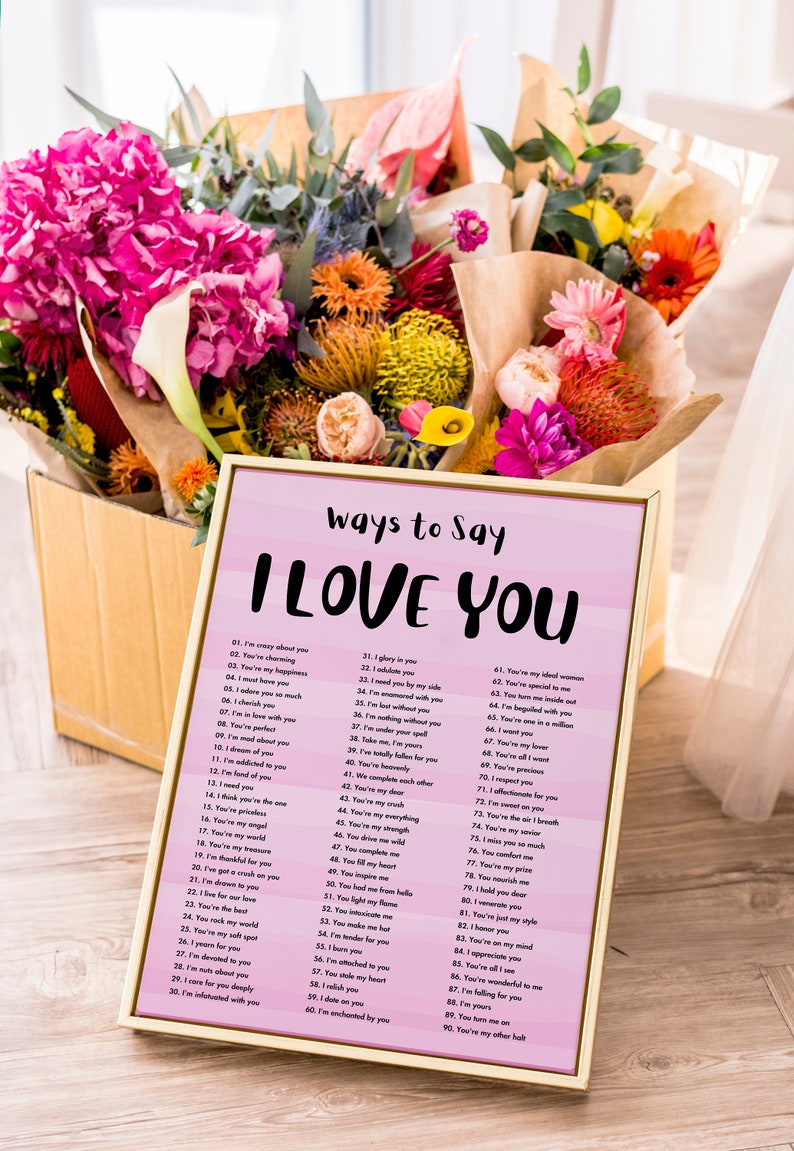 May include: A pink and white printable poster with a gold frame. The poster has the text "Ways to Say I Love You" at the top and a list of 90 different ways to say "I Love You".
