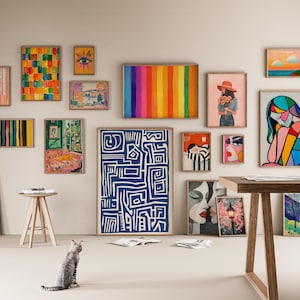 May include: A gallery wall with a variety of framed artwork, including abstract paintings, geometric designs, and portraits. The wall is painted a light beige color and the frames are all in a natural wood finish.
