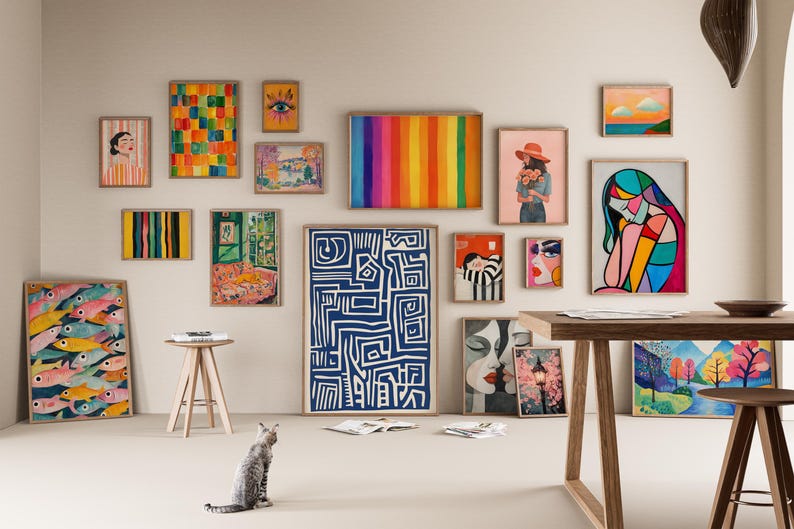 May include: A gallery wall with a variety of framed artwork, including abstract paintings, geometric designs, and portraits. The wall is painted a light beige color and the frames are all in a natural wood finish.
