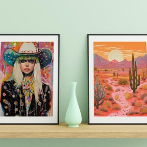 May include: Two framed art prints, one featuring a woman wearing a colorful cowboy hat and the other depicting a desert landscape with a tall cactus.
