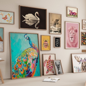 May include: A gallery wall featuring a variety of framed animal prints, including a peacock, a lion, a swan, a turtle, a donkey, a moose, a cat, a butterfly, a beetle, a snake, a dog, and an elephant. The prints are arranged in a grid pattern on a white wall.