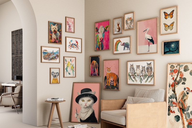 May include: A gallery wall with a variety of framed animal illustrations. The illustrations include a white dog, a pig, a crab, a koala, a cat, a tiger, a walrus, a cow, a bird, a group of owls, and a butterfly. The illustrations are framed in natural wood frames and are hung on a white wall.