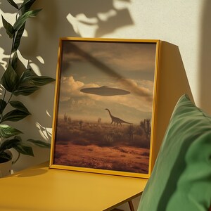 May include: A framed art print featuring a surreal landscape with a dinosaur and a UFO hovering in the sky. The artwork has a yellow frame and depicts a desert scene with mountains in the background. The color palette includes shades of brown, beige, and blue.