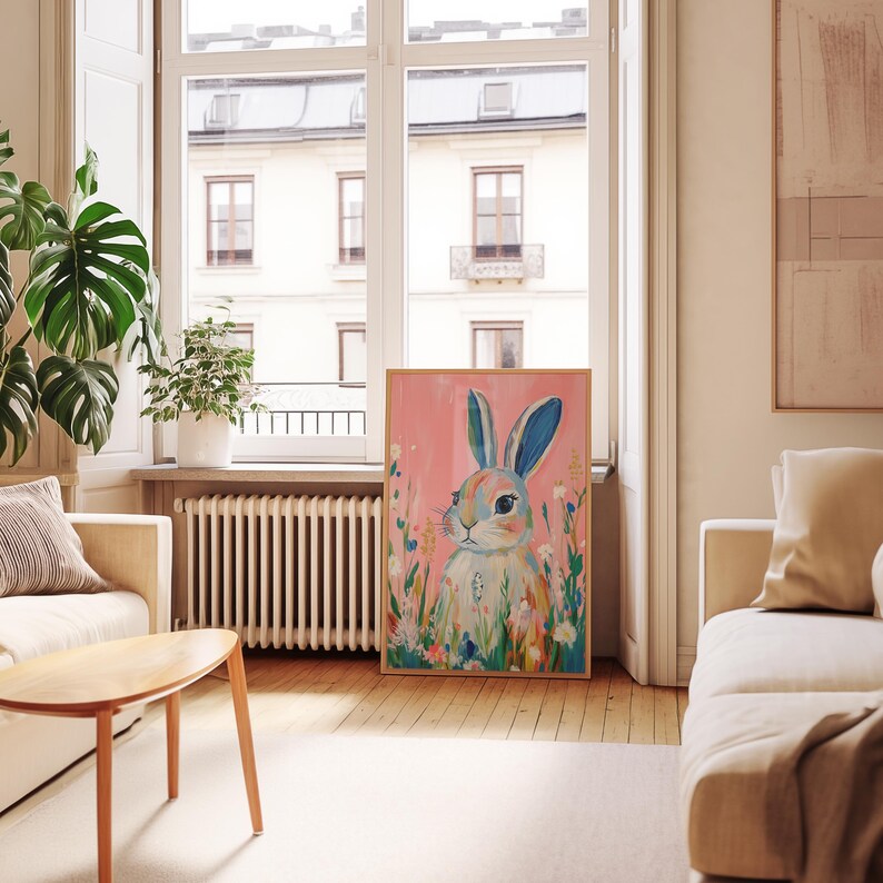 May include: A colorful painting of a rabbit with blue eyes and pink ears surrounded by flowers on a pink background.