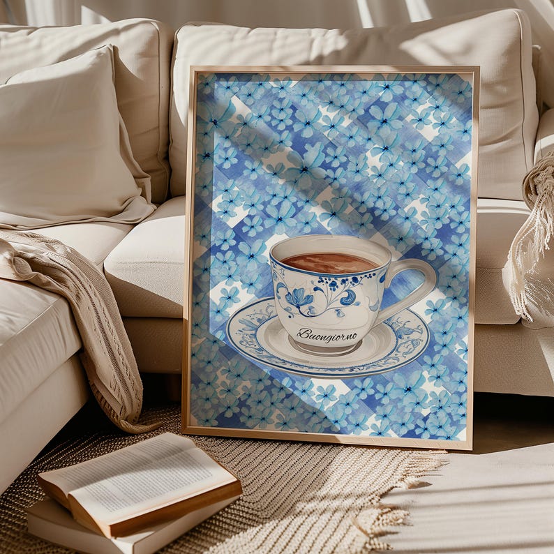 K&ouml;nnte beinhalten: Ein gerahmter Druck eines blauen und wei&szlig;en Aquarellbildes einer Tasse Kaffee mit dem Text "Buongiorno" auf der Untertasse. Der Hintergrund ist ein blaues und wei&szlig;es kariertes Muster mit kleinen blauen Blumen.
