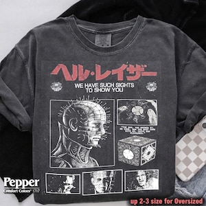May include: Dark gray Comfort Colors sweatshirt with a graphic from the movie Hellraiser. The design includes the text "ヘル・レイザー WE HAVE SUCH SIGHTS TO SHOW YOU" and images of the character Pinhead and the puzzle box.