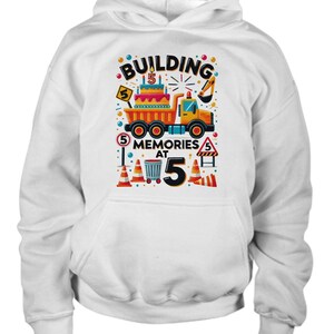 May include: White hoodie with a colorful graphic of a construction truck with a birthday cake on the back. The text on the graphic says "Building Memories at 5".
