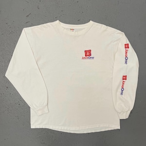 Puede incluir: Camiseta blanca de manga larga con el logo "JavaOne" en el pecho y las mangas. El logo presenta un diseño cuadrado rojo con el texto "JavaOne" en azul. Las mangas muestran el logo "JavaOne" verticalmente en rojo.