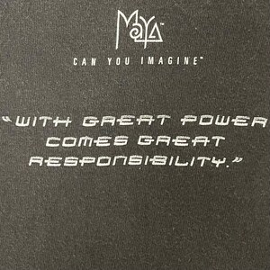 May include: Black t-shirt with white text. The top of the shirt has the word "Maya" above the phrase "Can You Imagine". Below, the shirt reads "With great power comes great responsibility."
