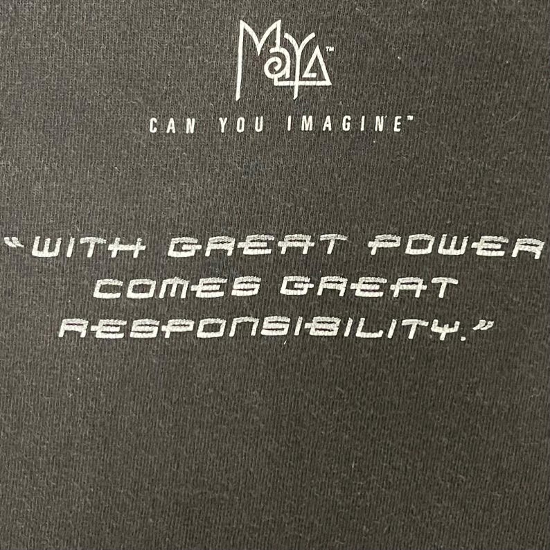 May include: Black t-shirt with white text. The top of the shirt has the word "Maya" above the phrase "Can You Imagine". Below, the shirt reads "With great power comes great responsibility."