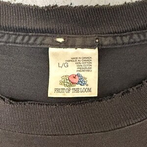 May include: Close-up of a dark grey t-shirt collar with a Fruit of the Loom label. The label reads "Made in Canada" and "100% Cotton." The label also features a graphic of an apple, grapes, and leaves. The shirt is size L/G.