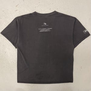 May include: Dark gray t-shirt with the text "WITH GREAT POWER COMES GREAT RESPONSIBILITY." in white. The shirt has a crew neck and short sleeves. A small logo is on the sleeve.