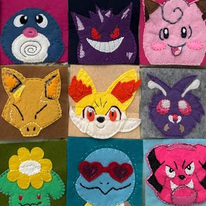 May include: A collection of colorful felt squares, each featuring a different cartoon character design. The characters are stitched with various colors and include a variety of creatures. The squares are arranged in a grid pattern.
